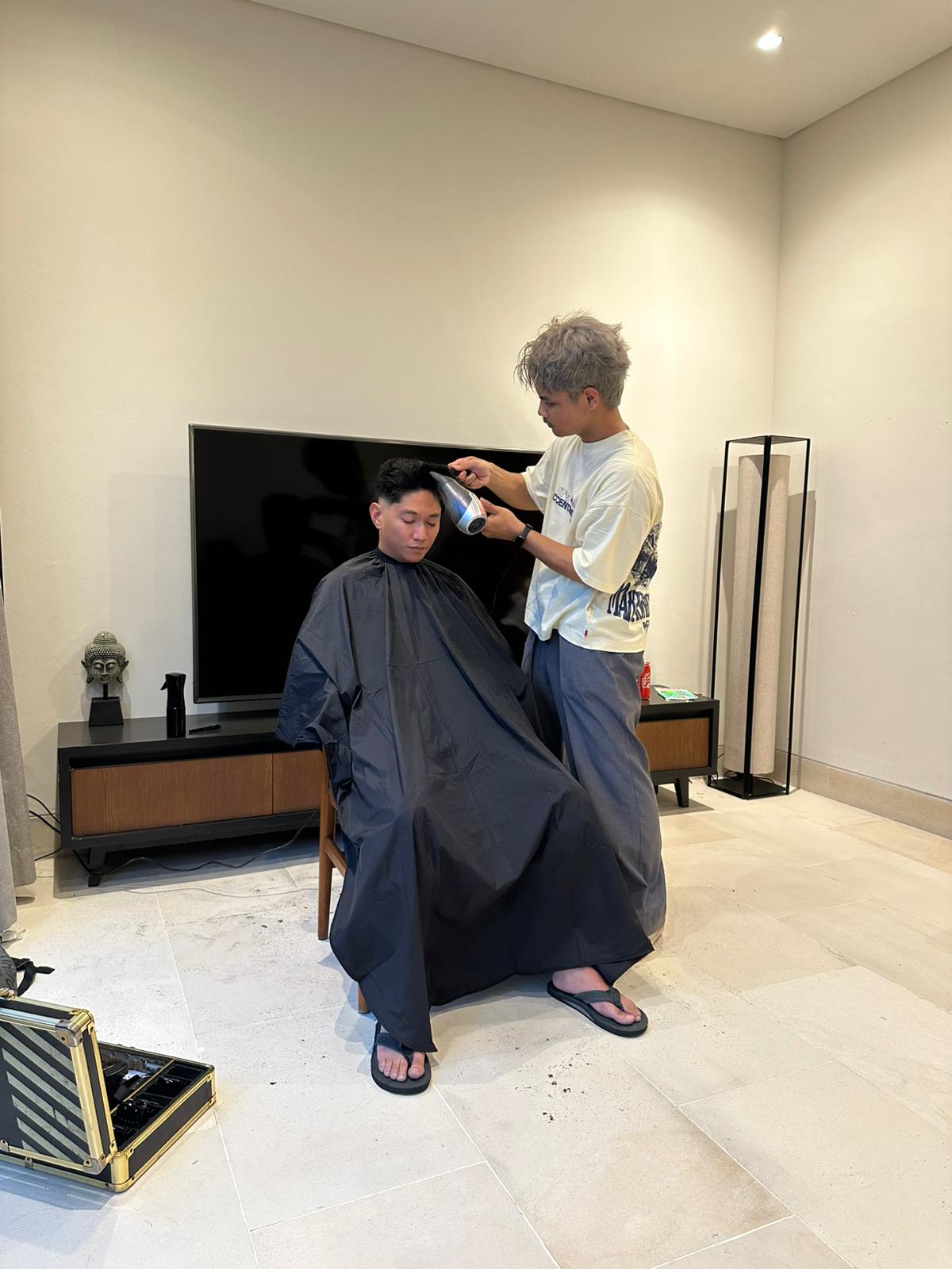 Barber blow-drying client hair during home service session